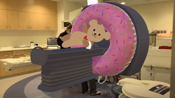 An augmented reality image of a donut and Choco Bear overlay an MRI machine