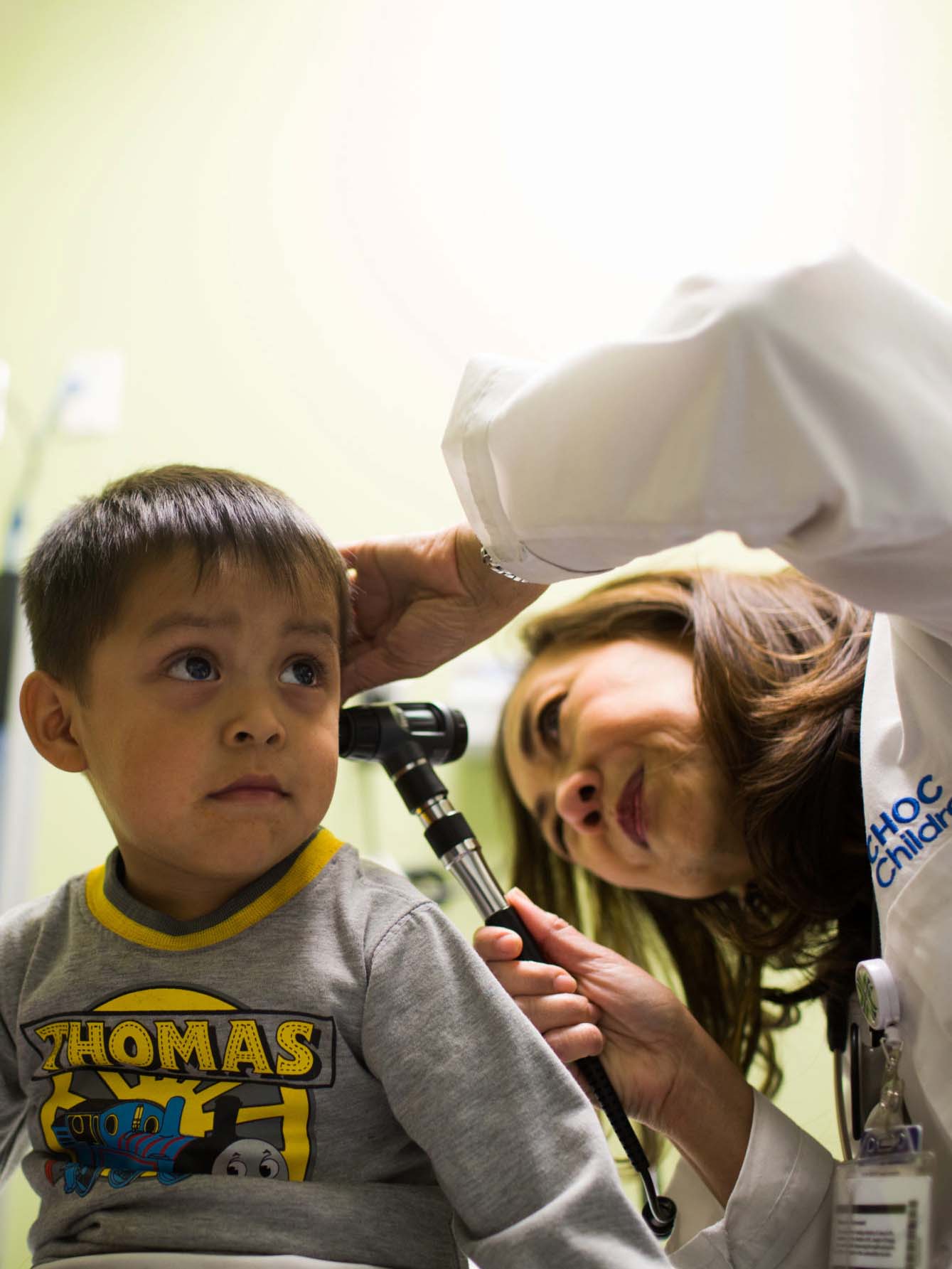 Female doctor looking inside male child's ear