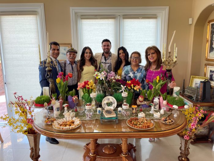 Tinoosh, her husband, her three grown children, and her parents pose behind a tablescape