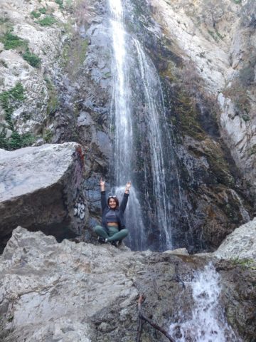 Patty Hernandez, EVS aide at CHOC, sits on a boulder in front of a waterfall