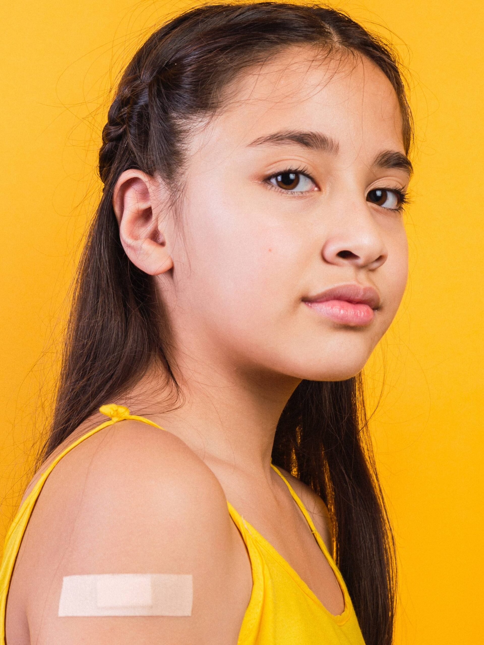 girl with dark hair and yellow shirt with bandage on arm