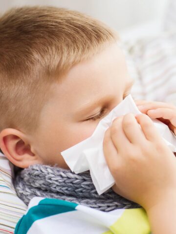 child sneezes into tissue