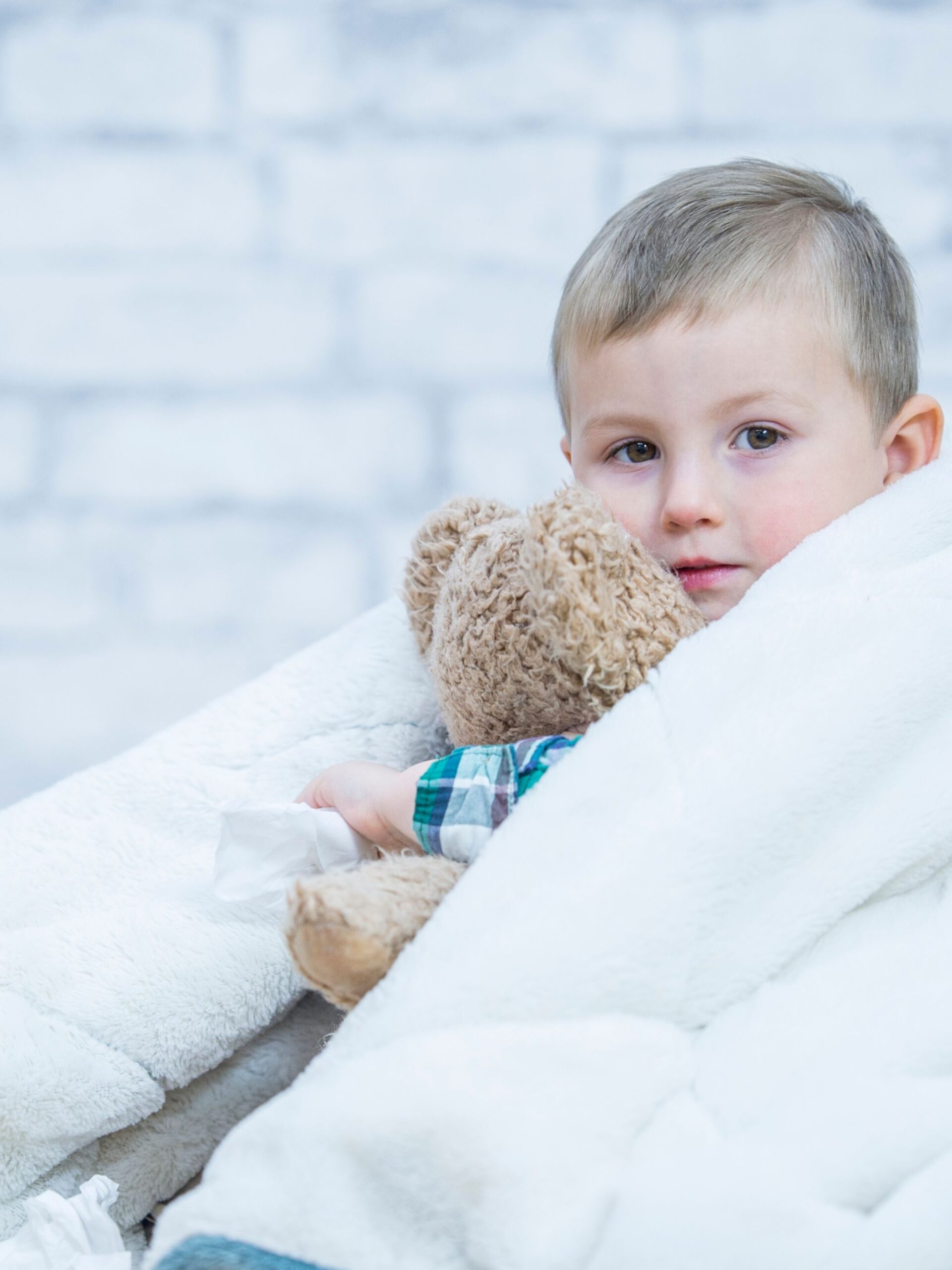 sick boy cuddles teddy bear