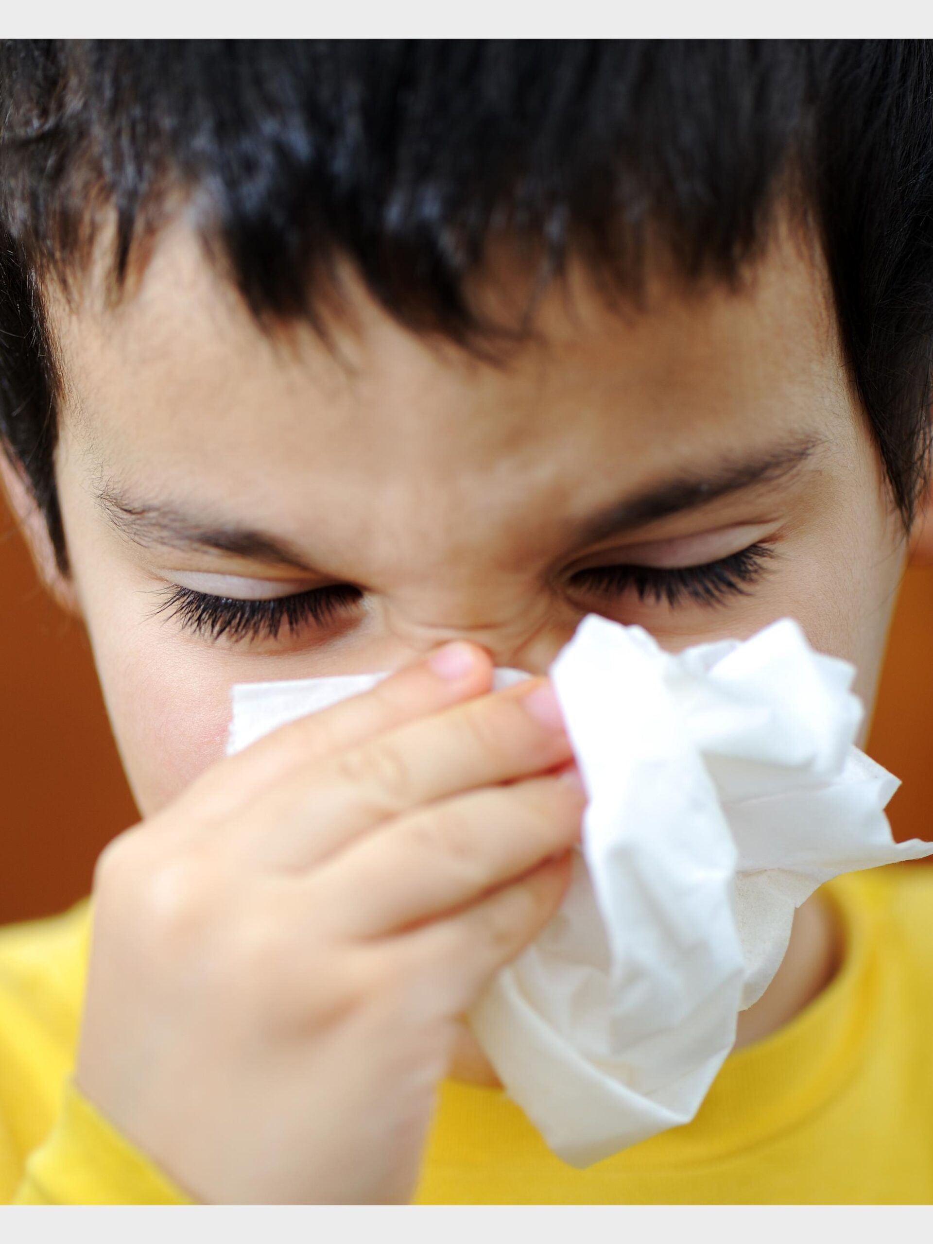 boy in yellow shirt blows his nose