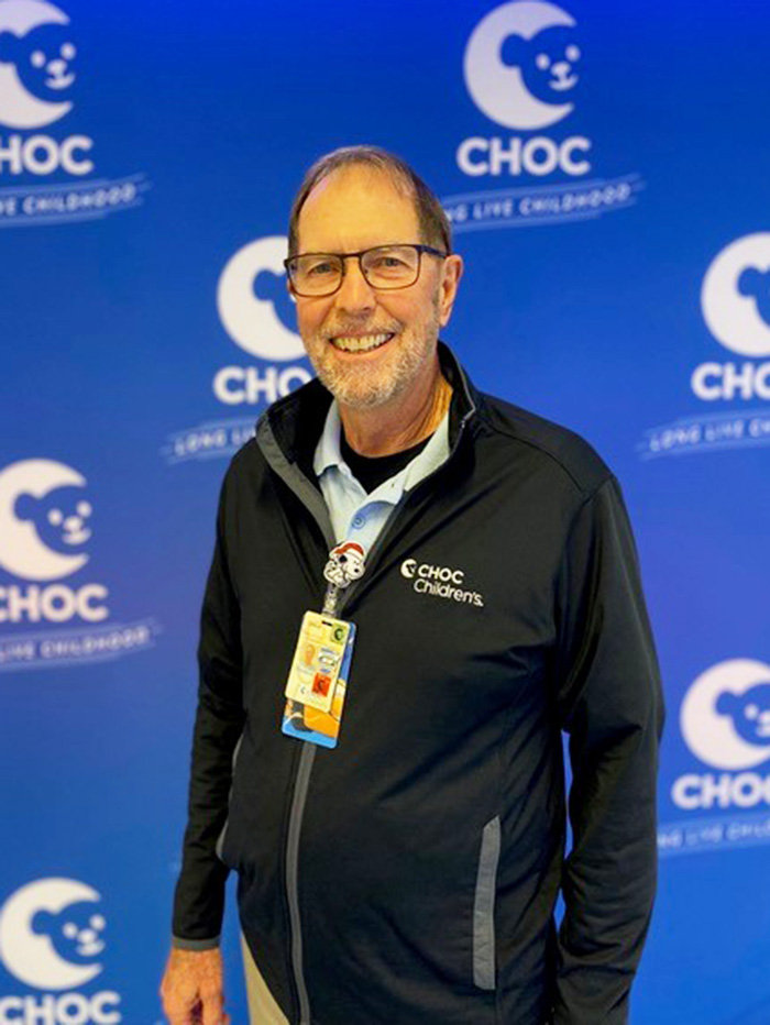 Steve Keller, CHOC volunteer, standing in front of CHOC background 