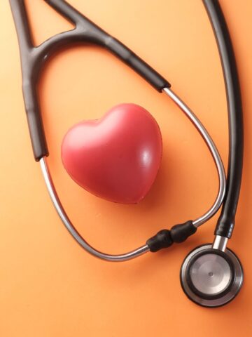 A stethoscope is positioned around a model heart
