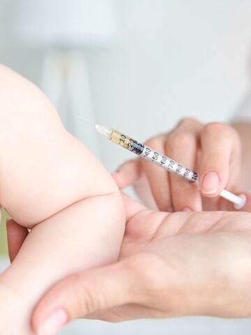Adult hand preparing to give a baby a vaccination