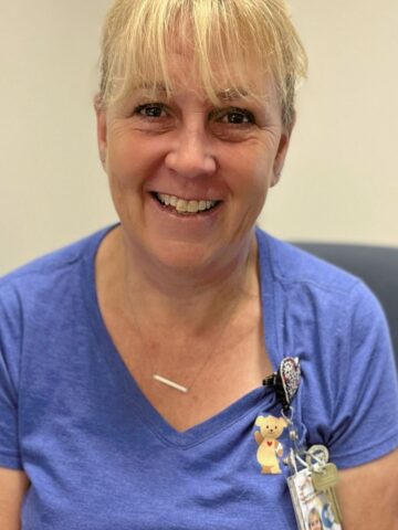 Smiling blond woman wearing blue nursing scrubs