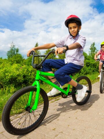 Boy riding green bike while wearing helmet