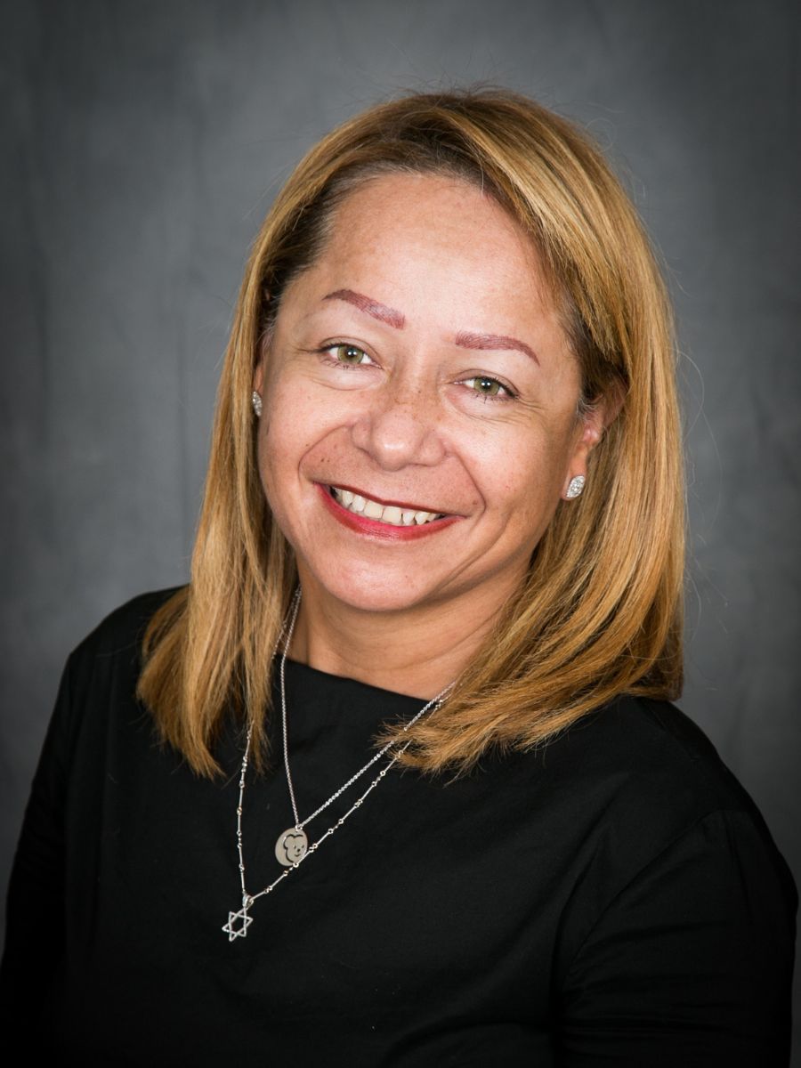 Smiling blond woman with green eyes and olive complexion wearing black blouse