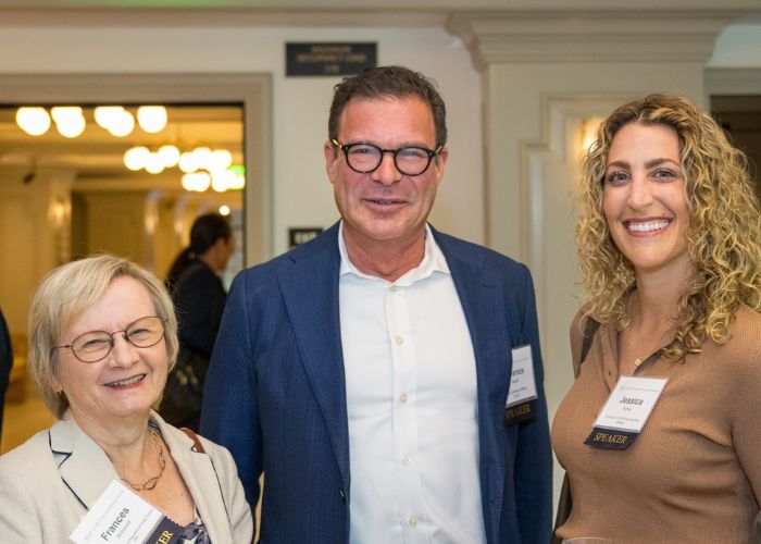 Two women and a man pose for a photo at an event