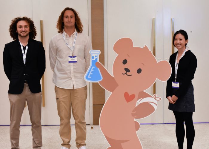 Three people pose with a cardboard bear