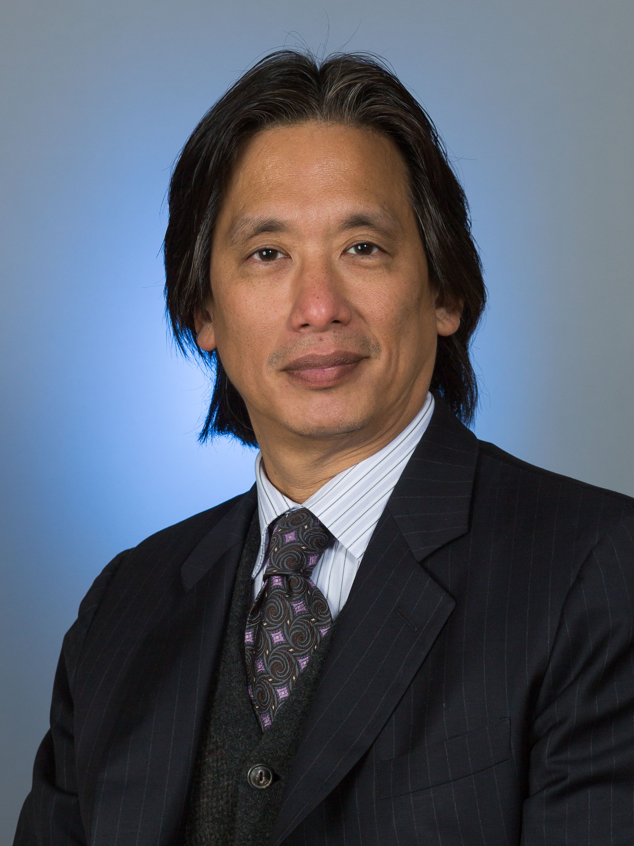 Man with dark hair wearing dark suit and tie