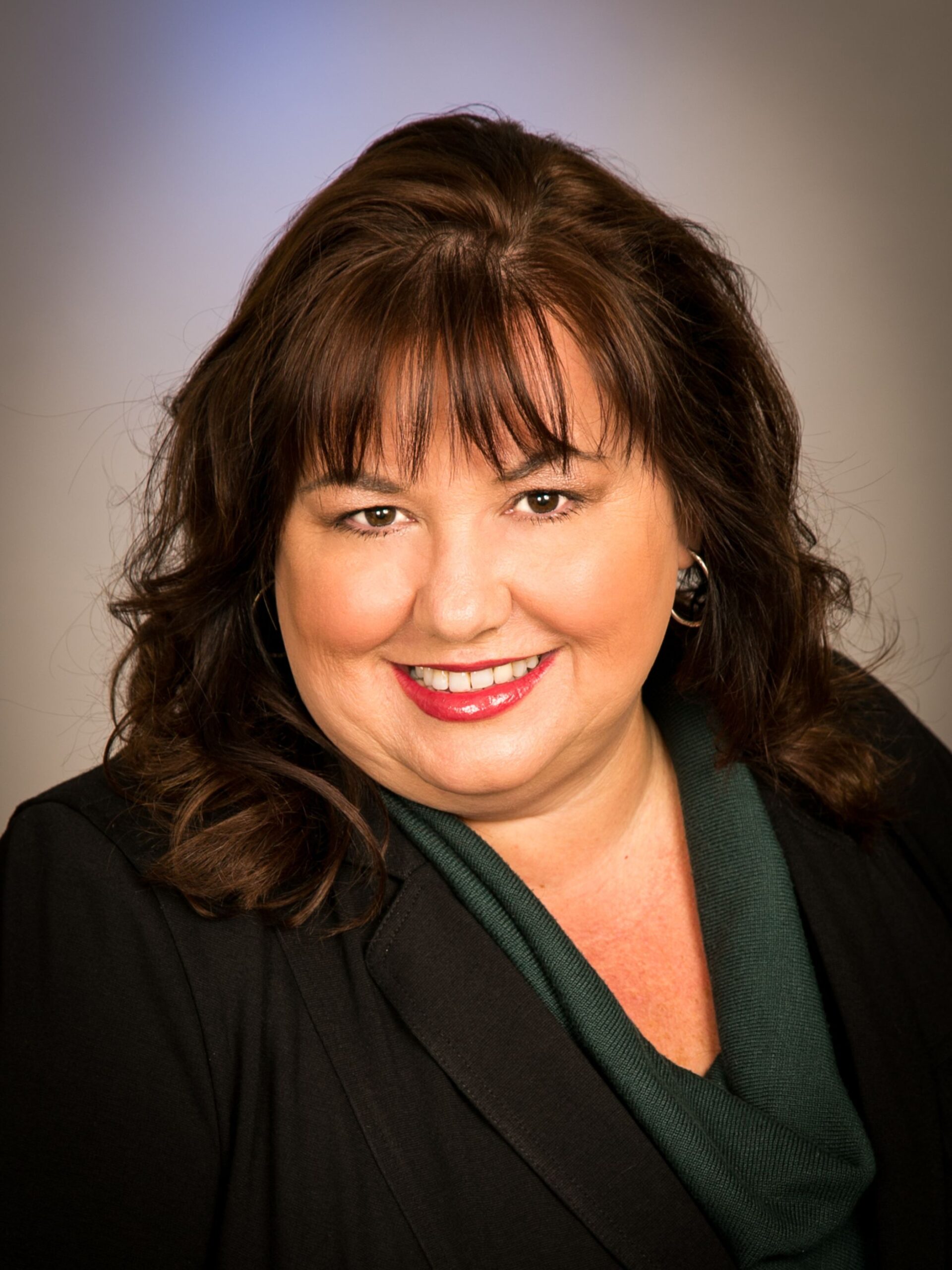 Woman with dark hair wearing black blazer and green blouse