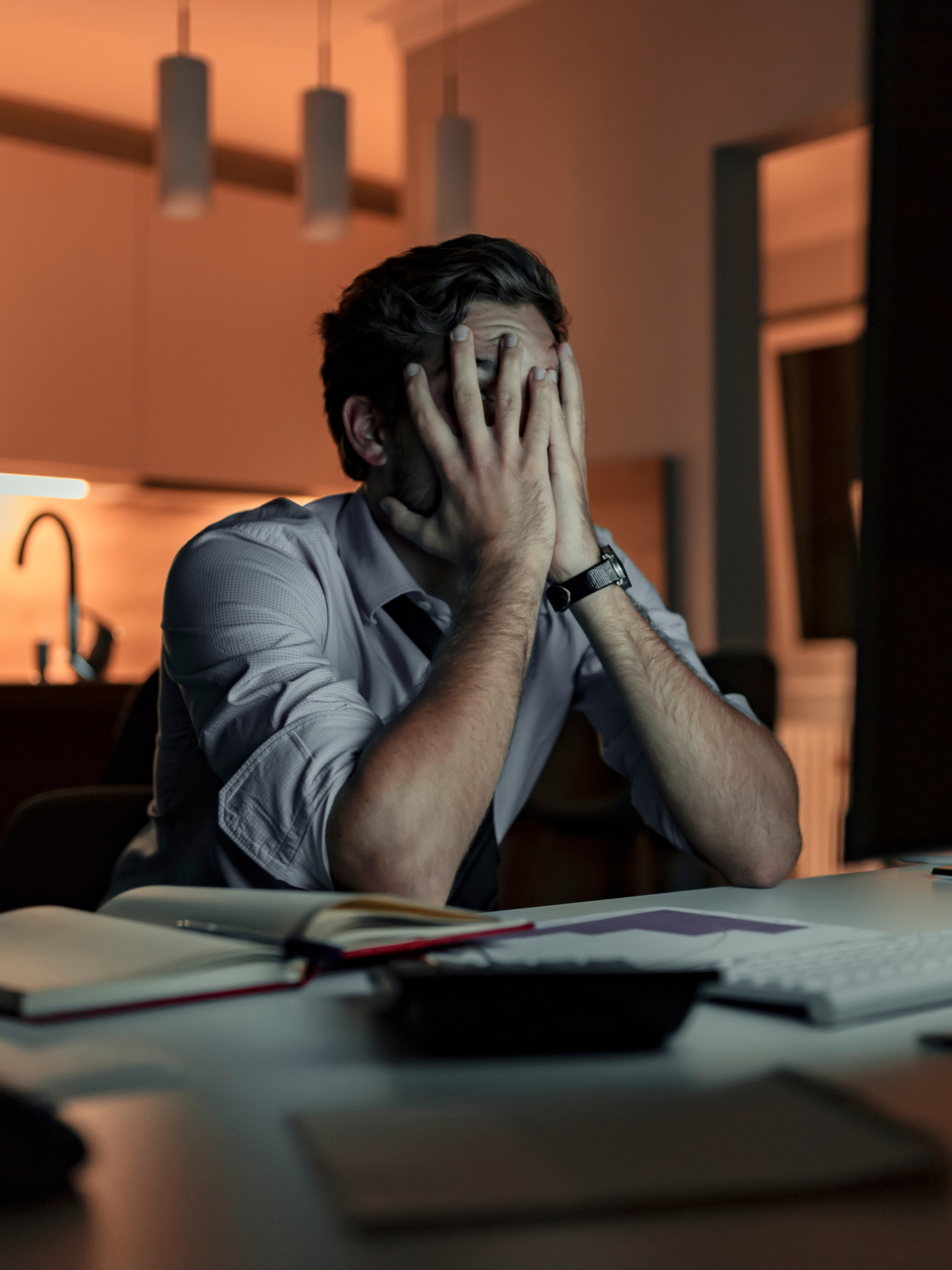 man at computer with hands covering face