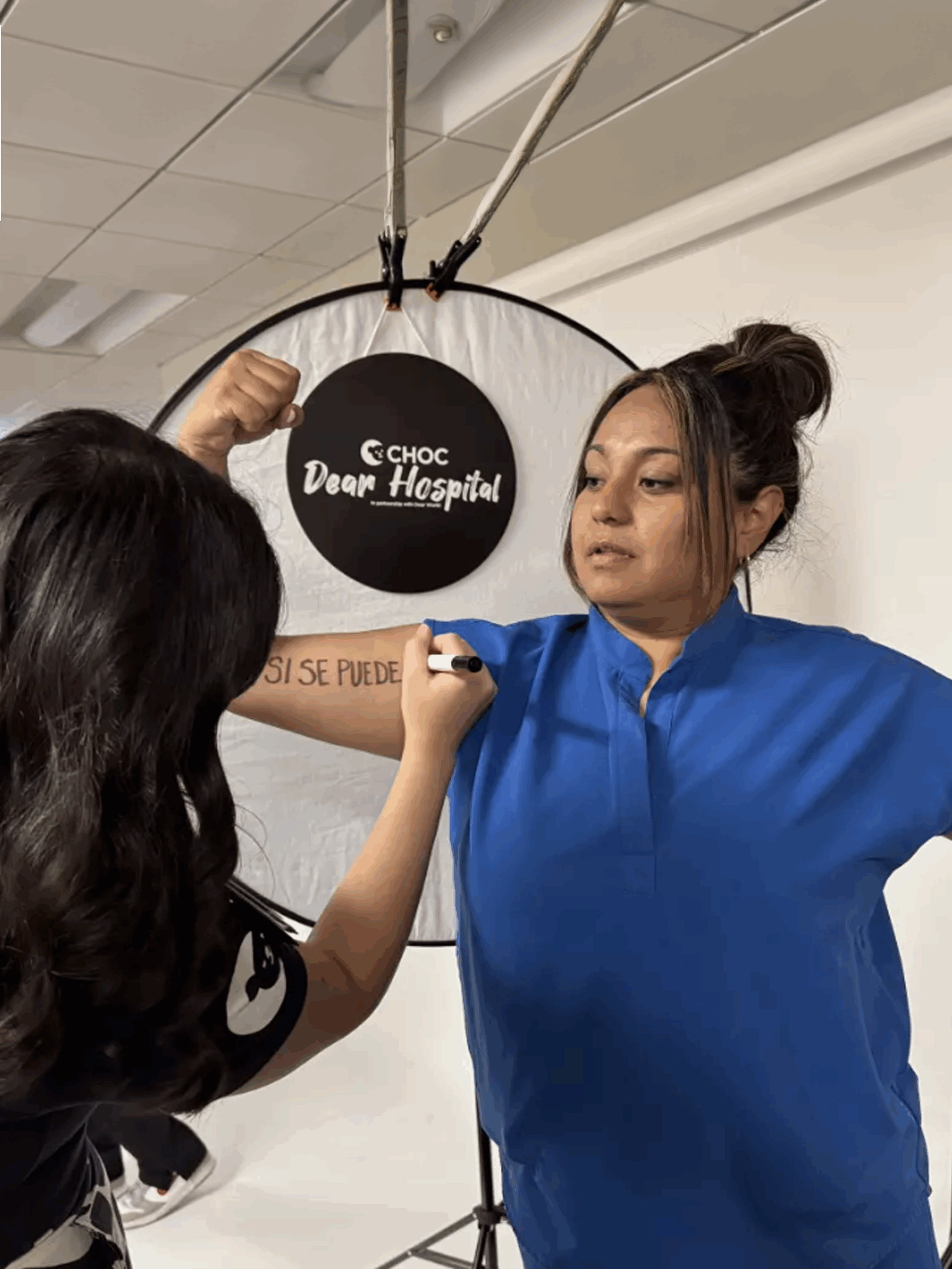Rebecca DeAnda writes the message “Si Se Puede” on Monica Gil’s arm during a CHOC new-hire orientation on May 6. (Jessica Peralta)