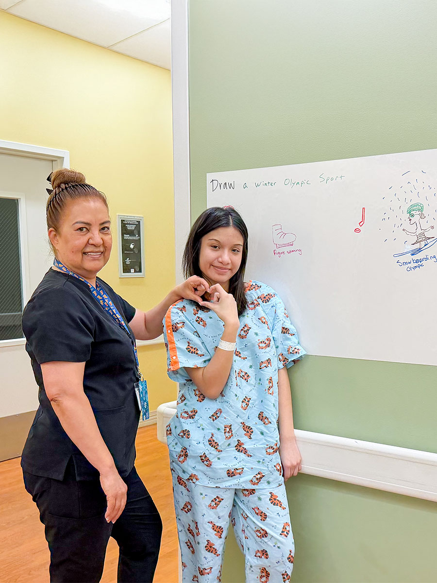 A mental health assistant and patient smile beside the patient’s whiteboard drawing.
