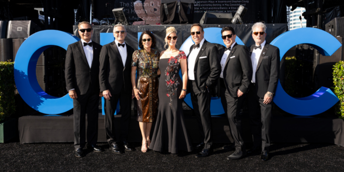 Group of formally dressed attendees pose together at gala