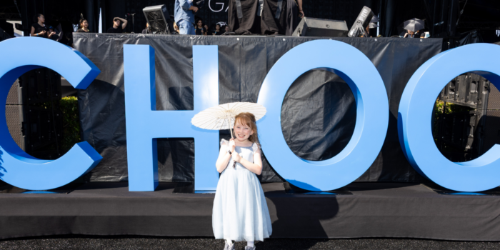 Young girl wearing white lacy dress and holding white parasol poses for photo